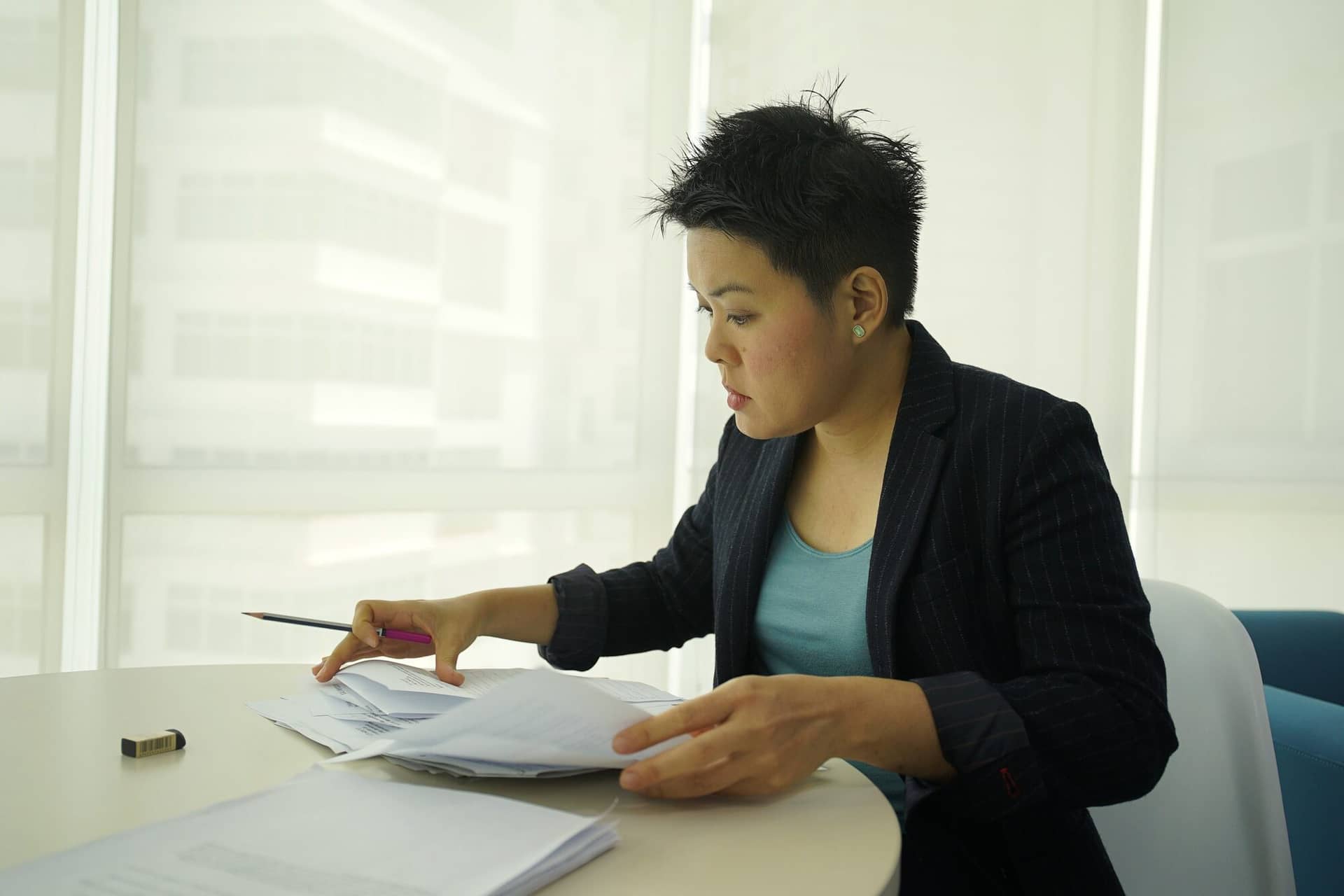 A practice owner reviews paperwork at a round table by a bright window.